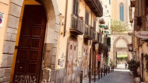 A narrow cobblestone street flanked by historic buildings with arched doorways and balconies. - Palazzo Rota Guesthouse (Naples)