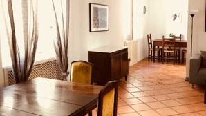 A dining area with a wooden table and chairs, a dark cabinet, and a patterned curtain. - Palazzo Rota Guesthouse (Naples)