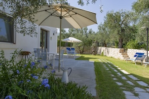 A patio with outdoor furniture, a large umbrella, and a stone wall.
