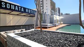 A SONATA HOTEL with a rooftop pool area, including lounge chairs and a poolside seating area.
