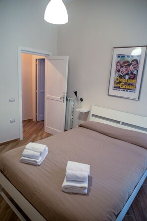 A bedroom with a bed, a door, a radiator, and a poster on the wall. - GuestHouse Marcanto - Duomo (Naples)