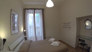 A bedroom with a bed, a desk, a chair, a mirror, and a window with curtains. - GuestHouse Marcanto - Duomo (Naples)