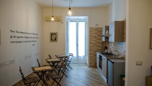A compact kitchen with modern appliances, a dining area with foldable chairs, and a wall with a decorative quote. - GuestHouse Marcanto - Duomo (Naples)