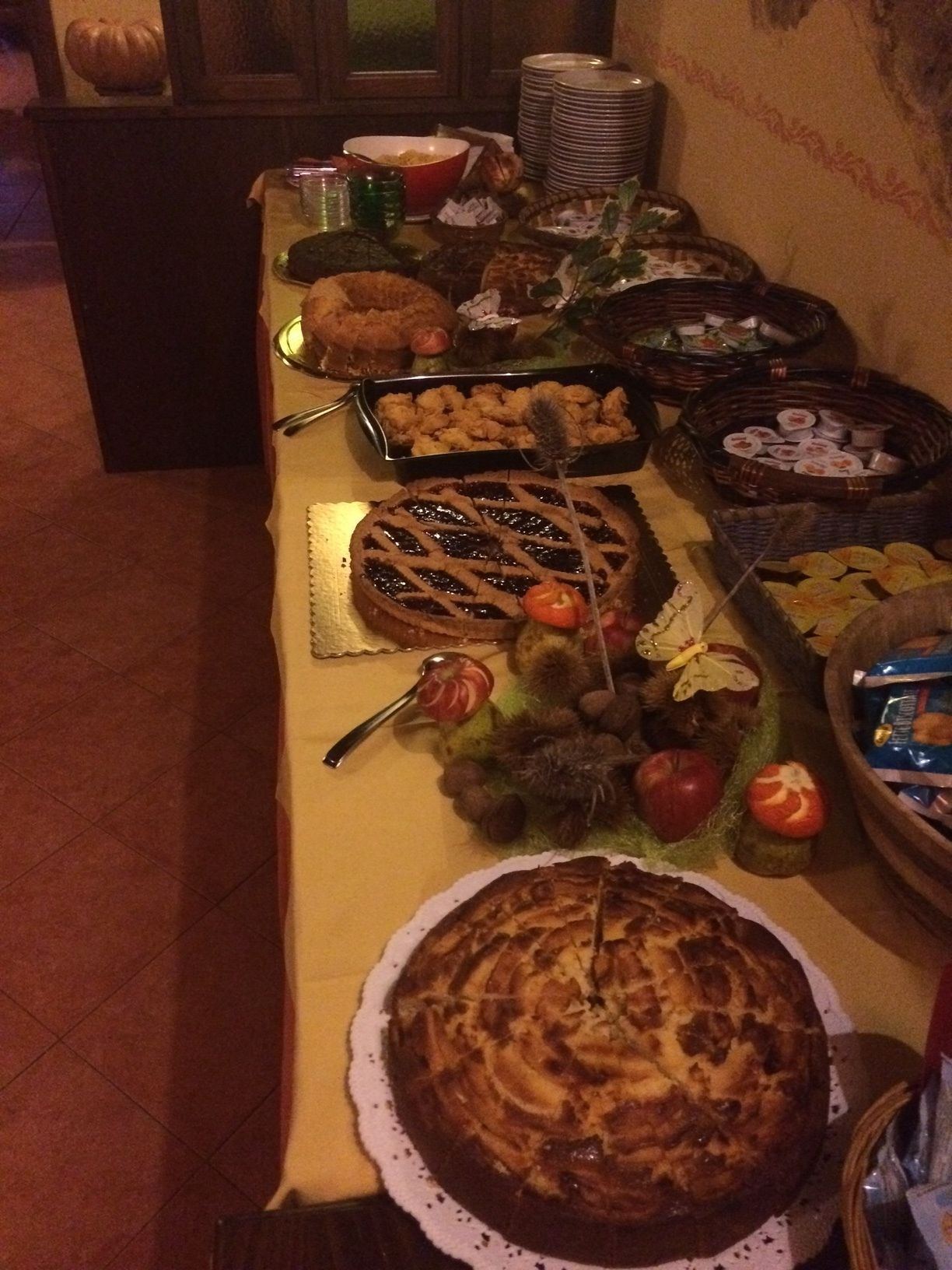 Un tavolo per buffet con diversi piatti, tra cui una torta grande, frutta e altri alimenti.