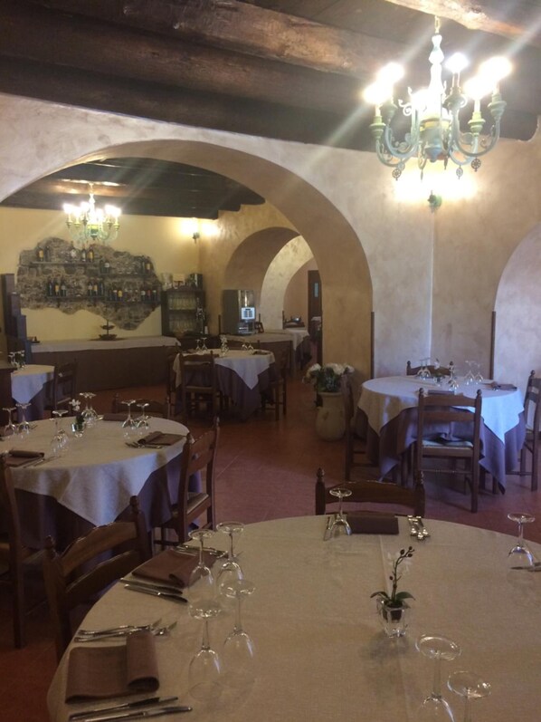 A restaurant with round tables set for dining, featuring wine glasses and cutlery. - La Locanda di San Francesco (Viggianello)