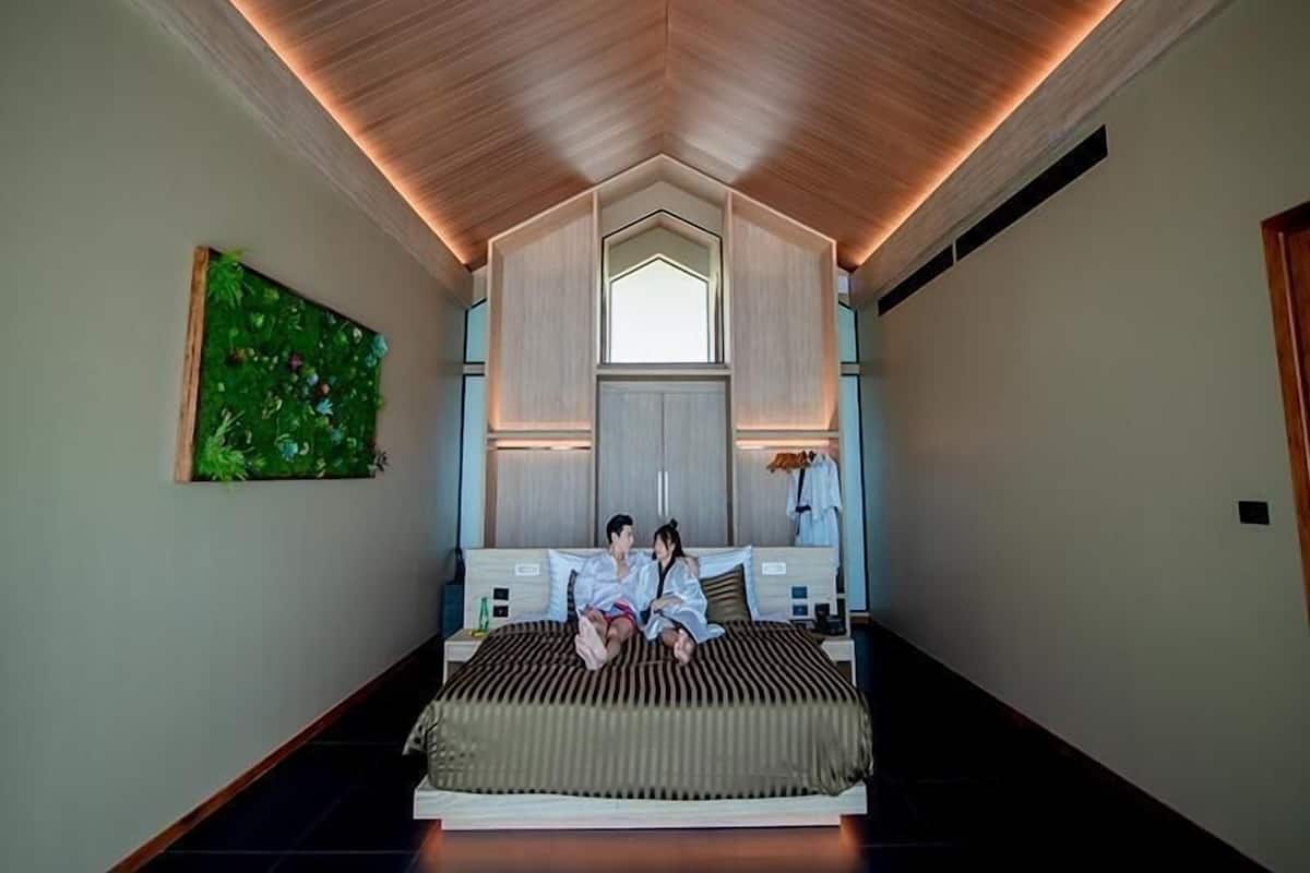 A bedroom with a bed, a green wall art, a window, and a wooden ceiling.