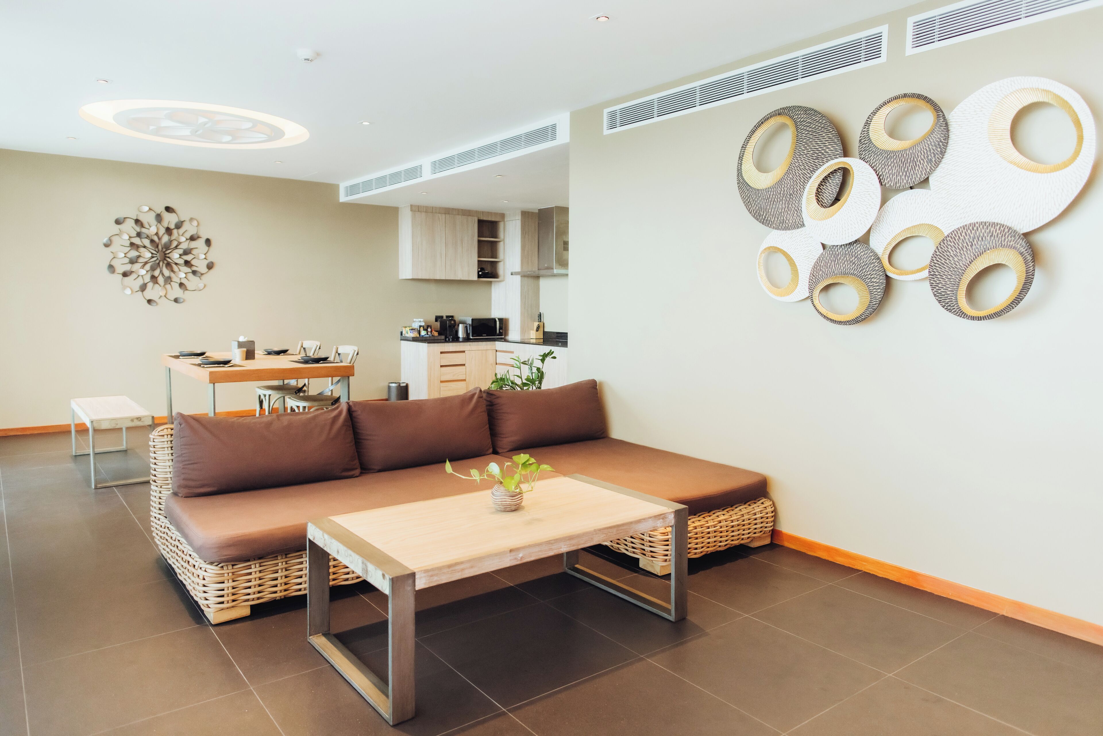 A modern living room with a sofa, a coffee table, and a kitchen in the background.