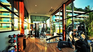 Ein Fitnessstudio mit Trainingsgeräten, großen Fenstern und Blick auf Gebäude.