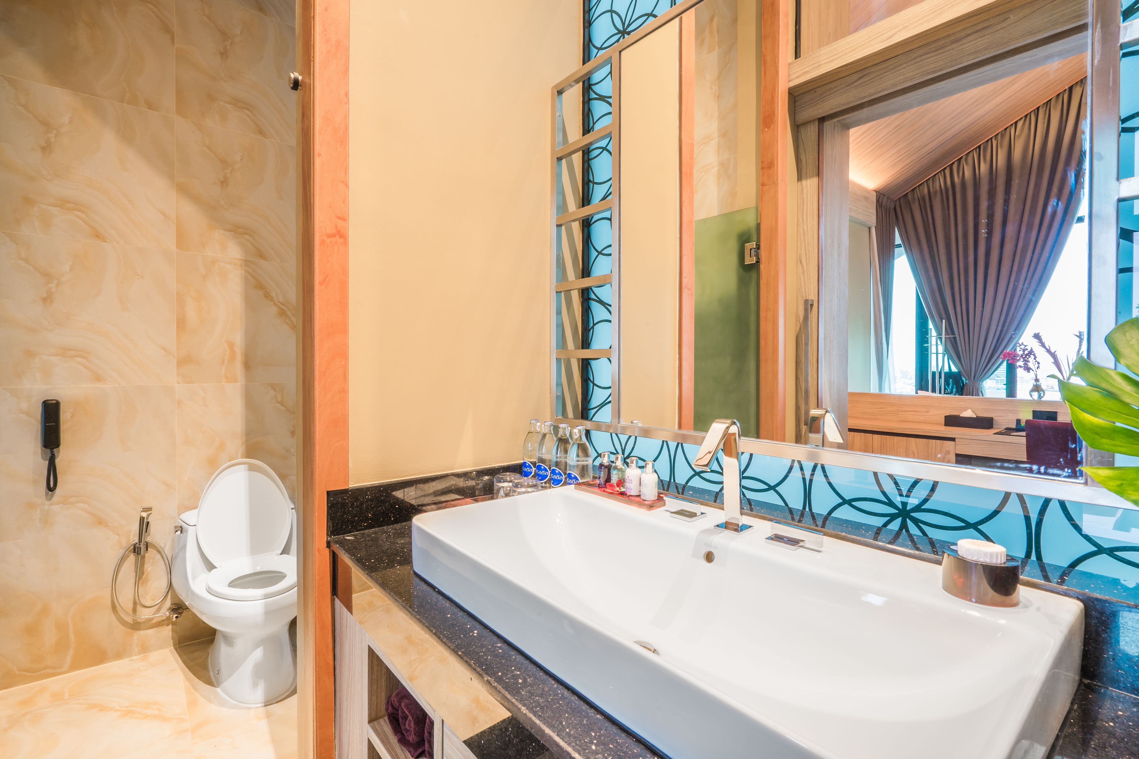 A bathroom with a large sink, a toilet, and a mirror.