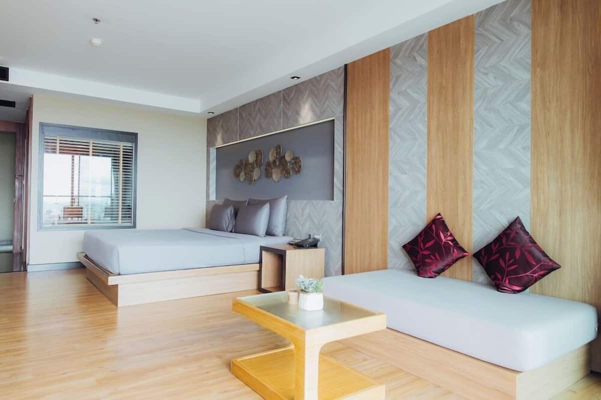 A modern bedroom with a bed, a sofa, a small table, and a decorative wall piece.