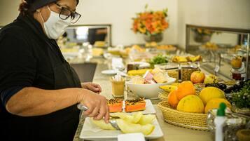 Un bufé con diferentes alimentos y una persona sirviendo.