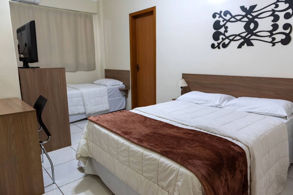 Ein Hotelzimmer mit Bett, Schreibtisch, Stuhl, Fernseher und einer Tür.