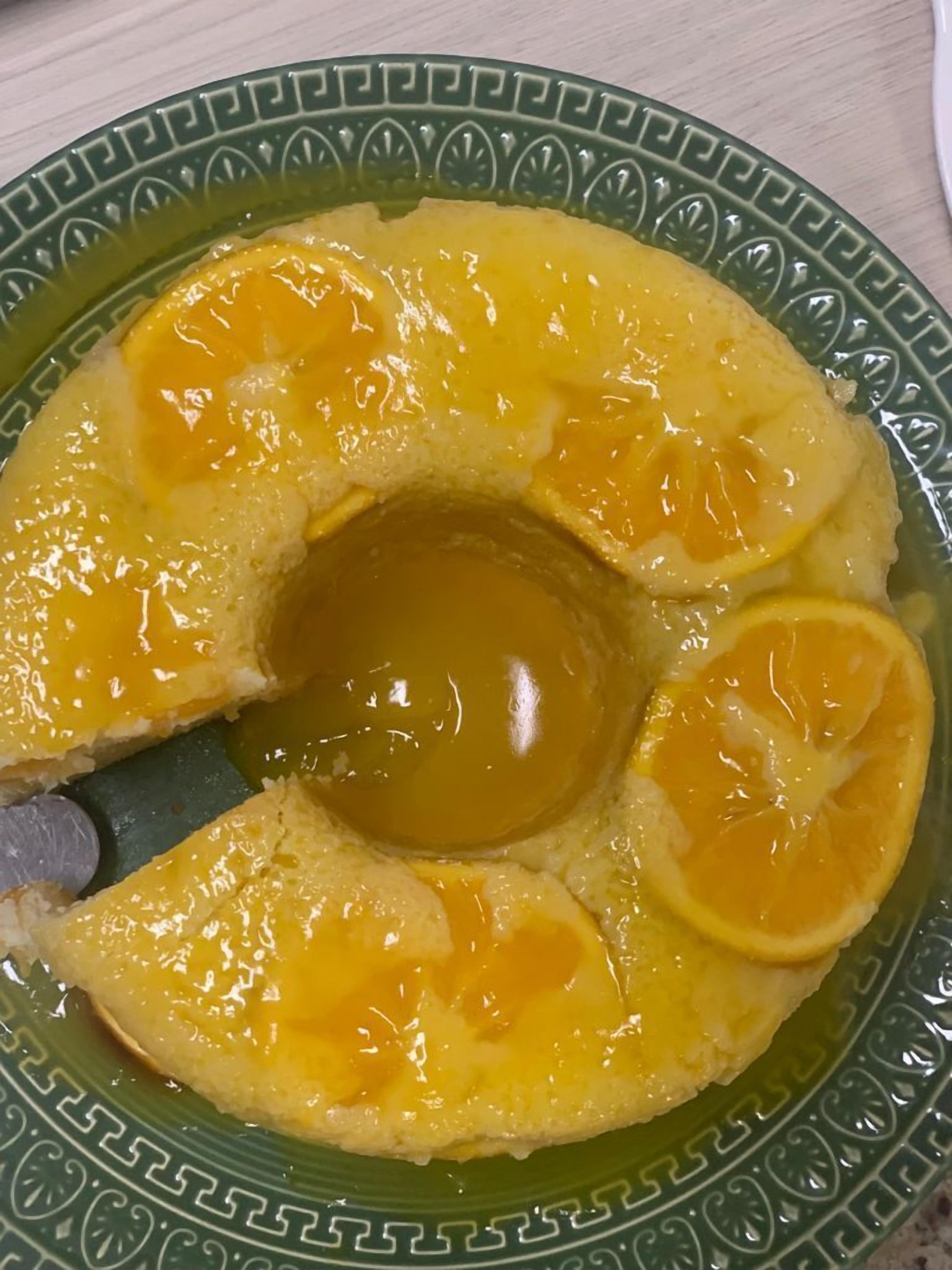 Un plato con un postre que tiene un hueco central, rodeado de rodajas de naranja.