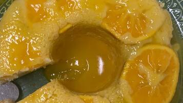 Un plato con un postre que tiene un hueco central, rodeado de rodajas de naranja.