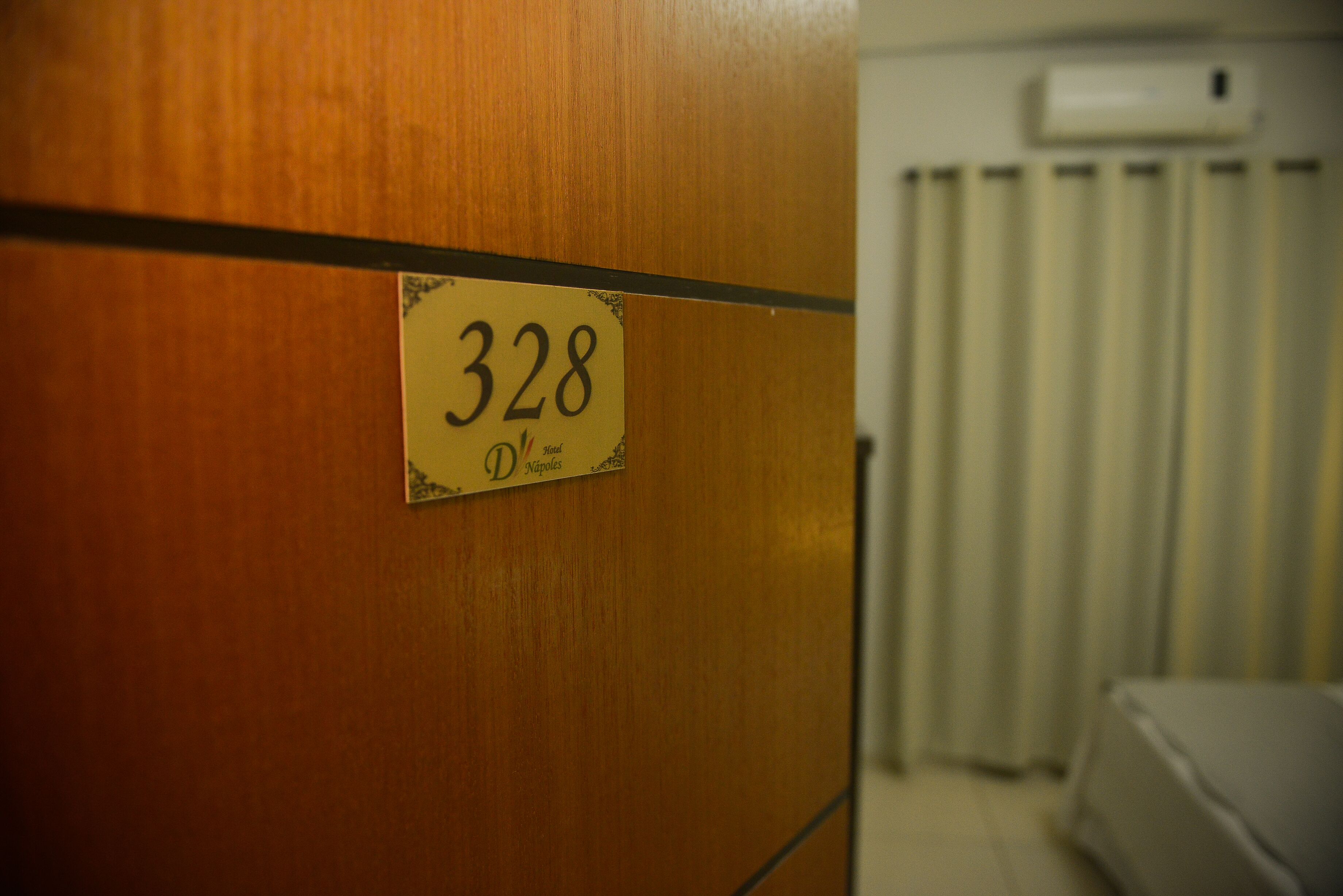 A room with a wooden door, a sign with the number 328, and a radiator in the background.