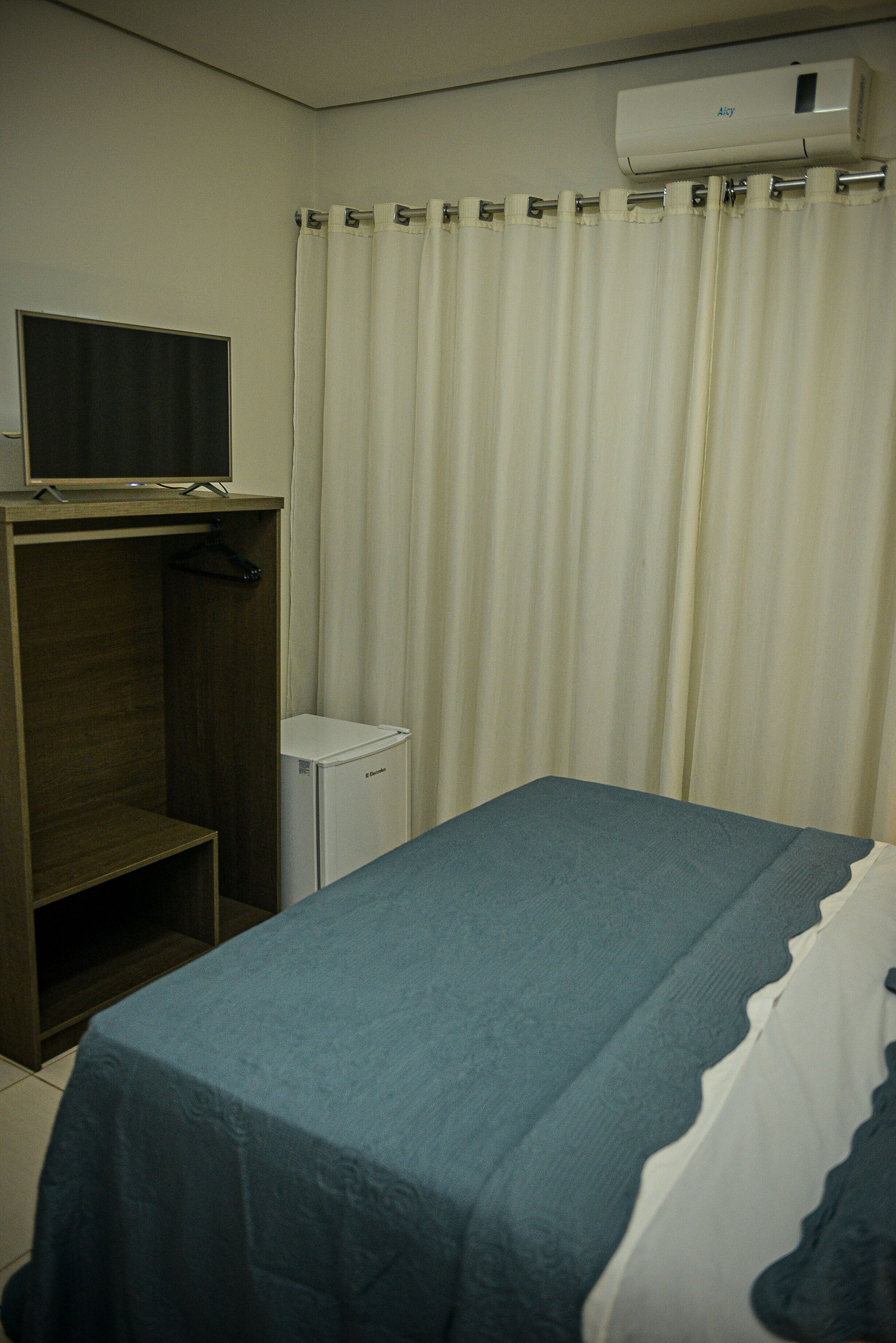 A hotel room with a bed, a small table, a wardrobe, and a television.
