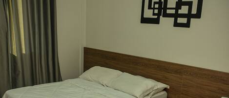 Une chambre d’hôtel avec deux lits, une tête de lit en bois, une table de chevet et un climatiseur fixé au mur.