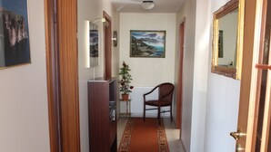 A hallway with a patterned carpet, wooden doors, a television, and a framed picture on the wall. - Sunnuberg Guesthouse (Skagafjörour)