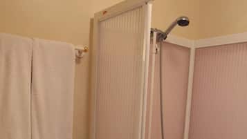 Un baño con inodoro, cabina de ducha y perchero para toallas.