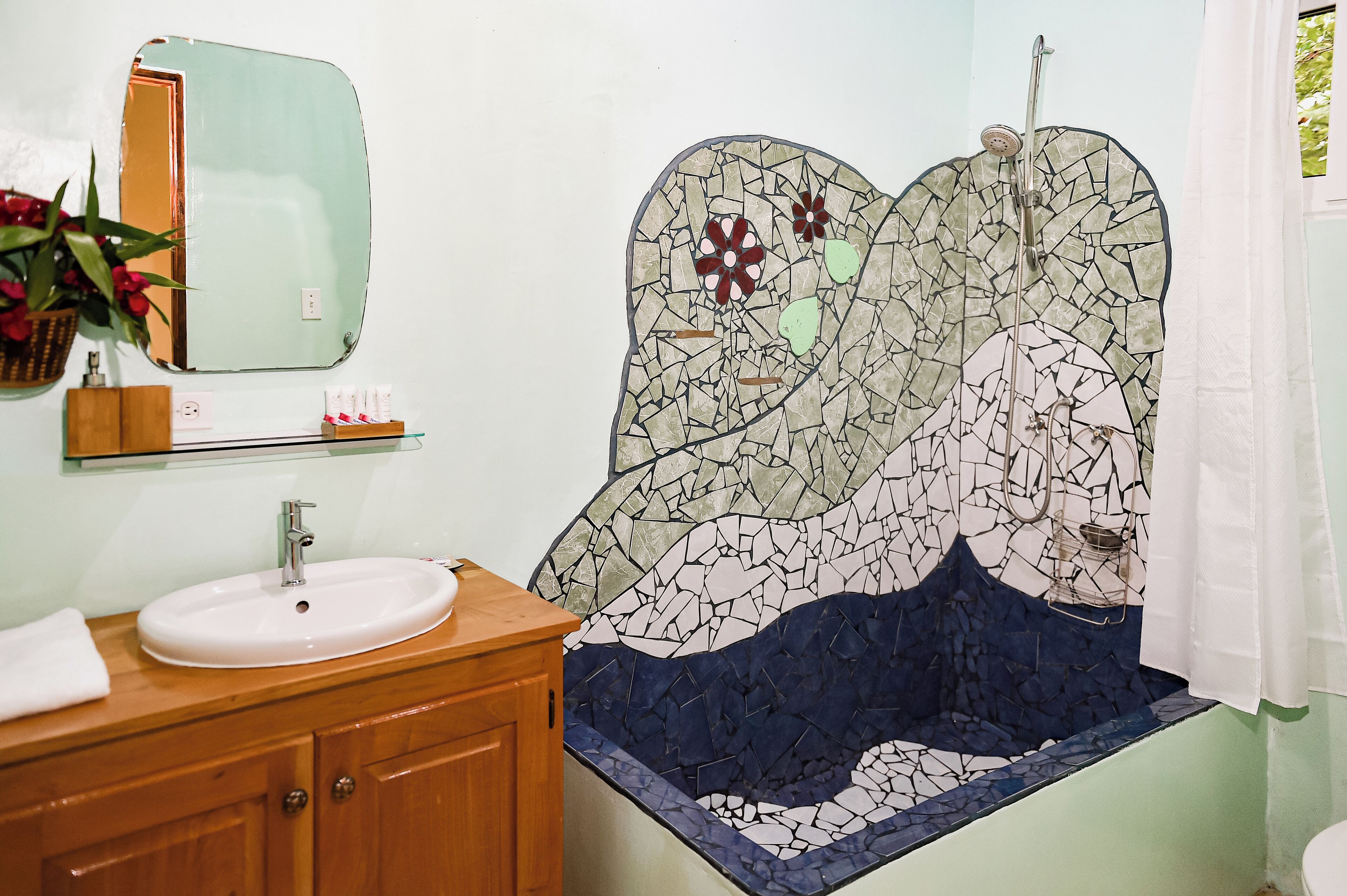 A bathroom with a mosaic sink, wooden vanity, and a large mirror.