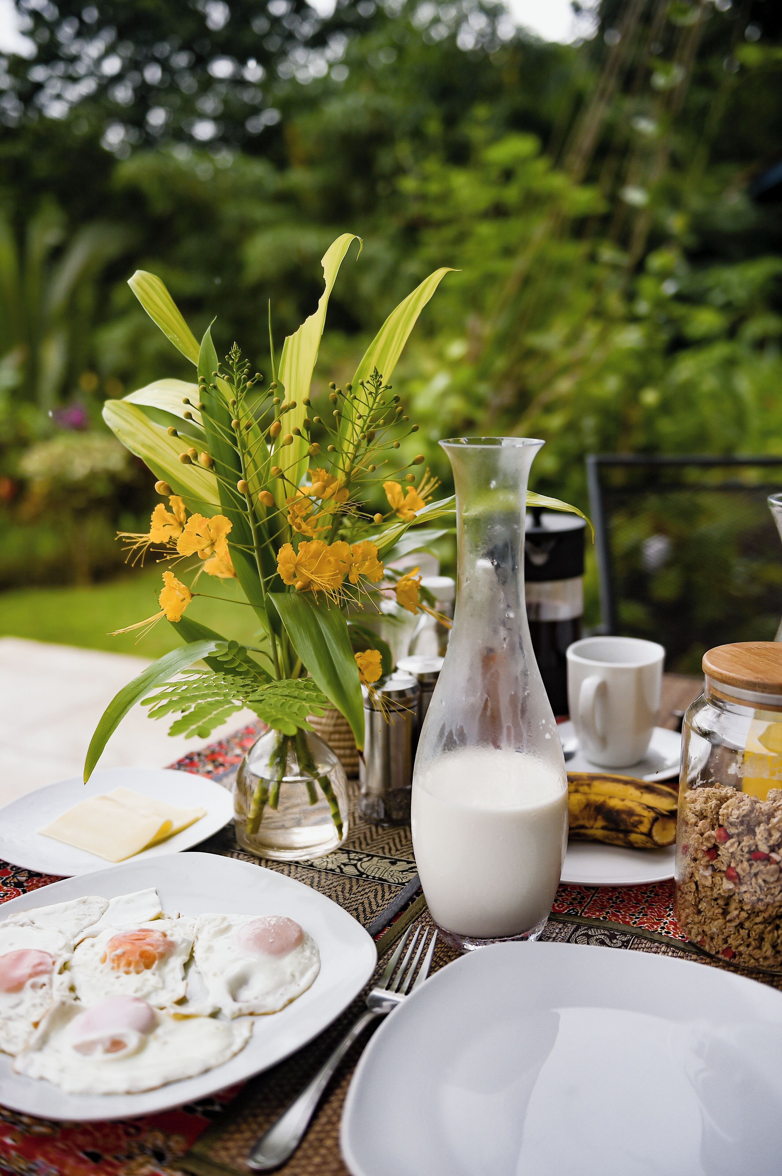 Un desayuno con huevos, leche y un jarrón de flores.