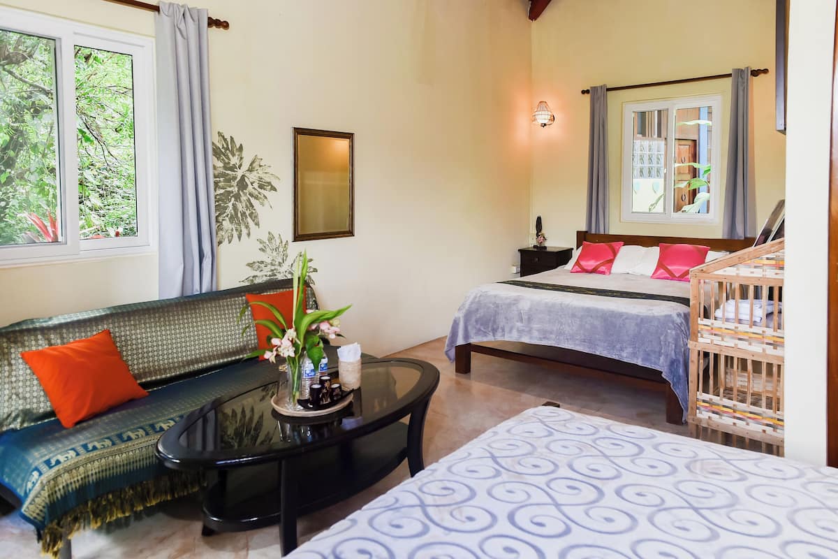 Una habitación con sofá, cama, una mesita y una cuna.