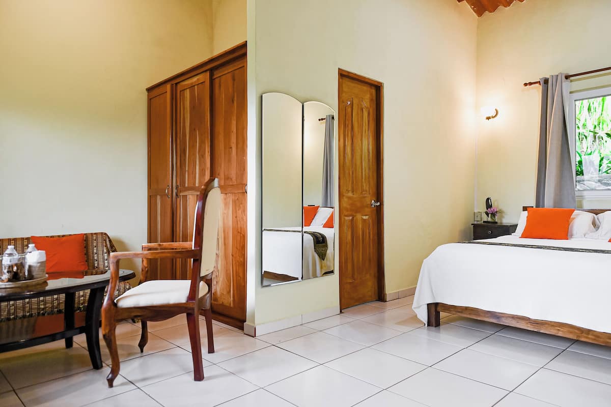 Un dormitorio con cama, un armario de madera, una mesa con silla y un espejo.