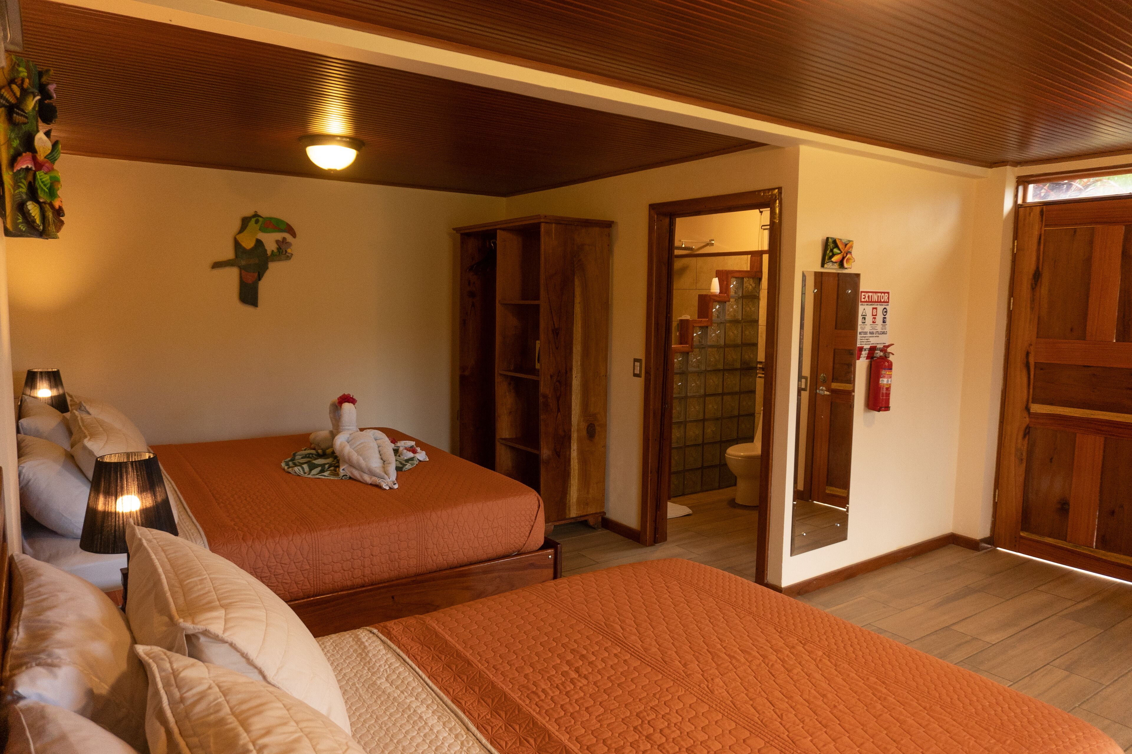 Ein Hotelzimmer mit zwei Betten, Holzboden, einer kleinen Pflanze und einem Holzschrank.