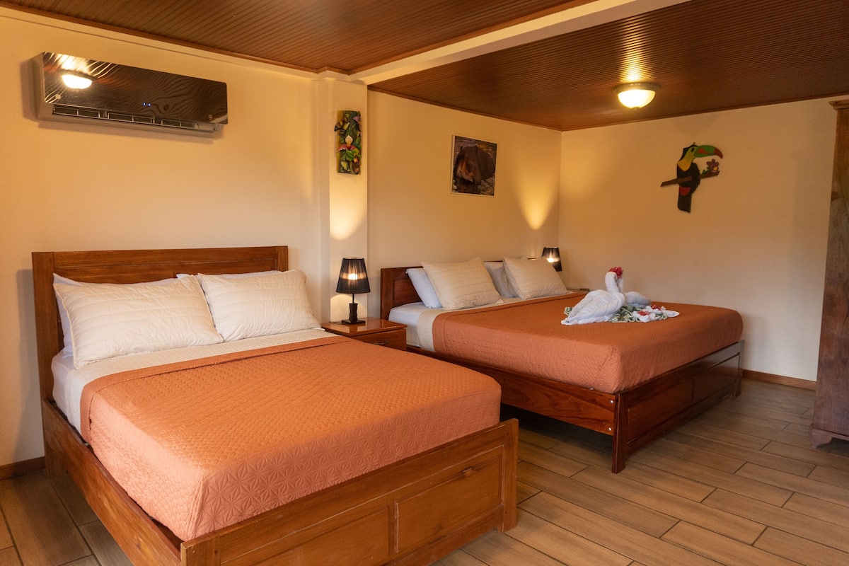 A hotel room with two wooden beds, each with a matching headboard and footboard, and a nightstand with a lamp.