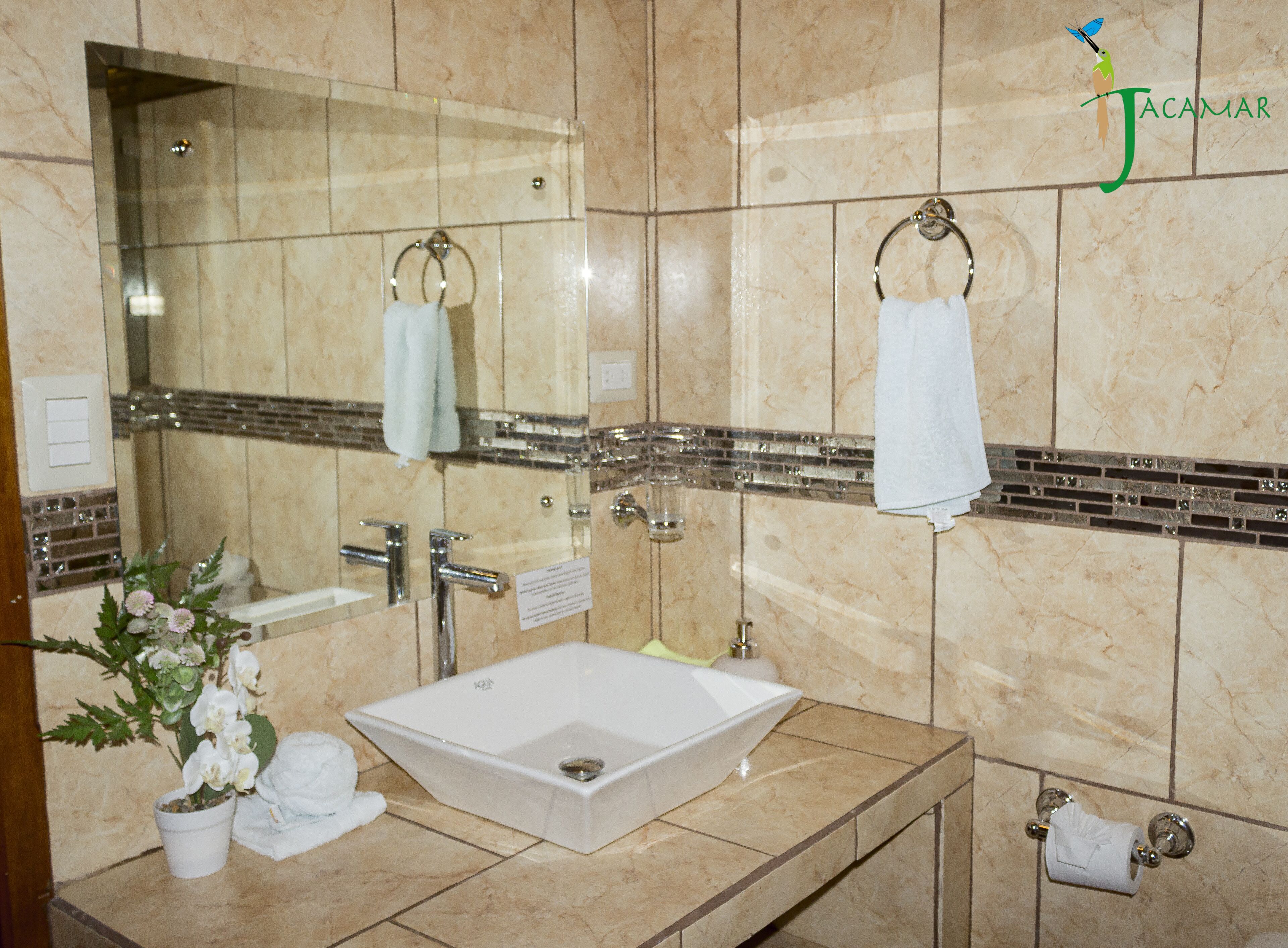 Une salle de bain avec un grand miroir, un lavabo et un porte-serviettes.