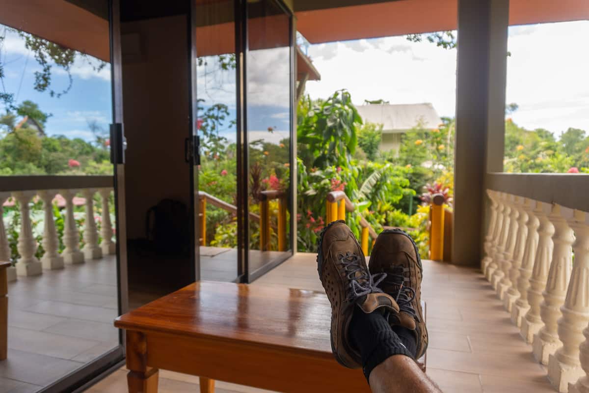 A balcony with a wooden table and a pair of shoes.