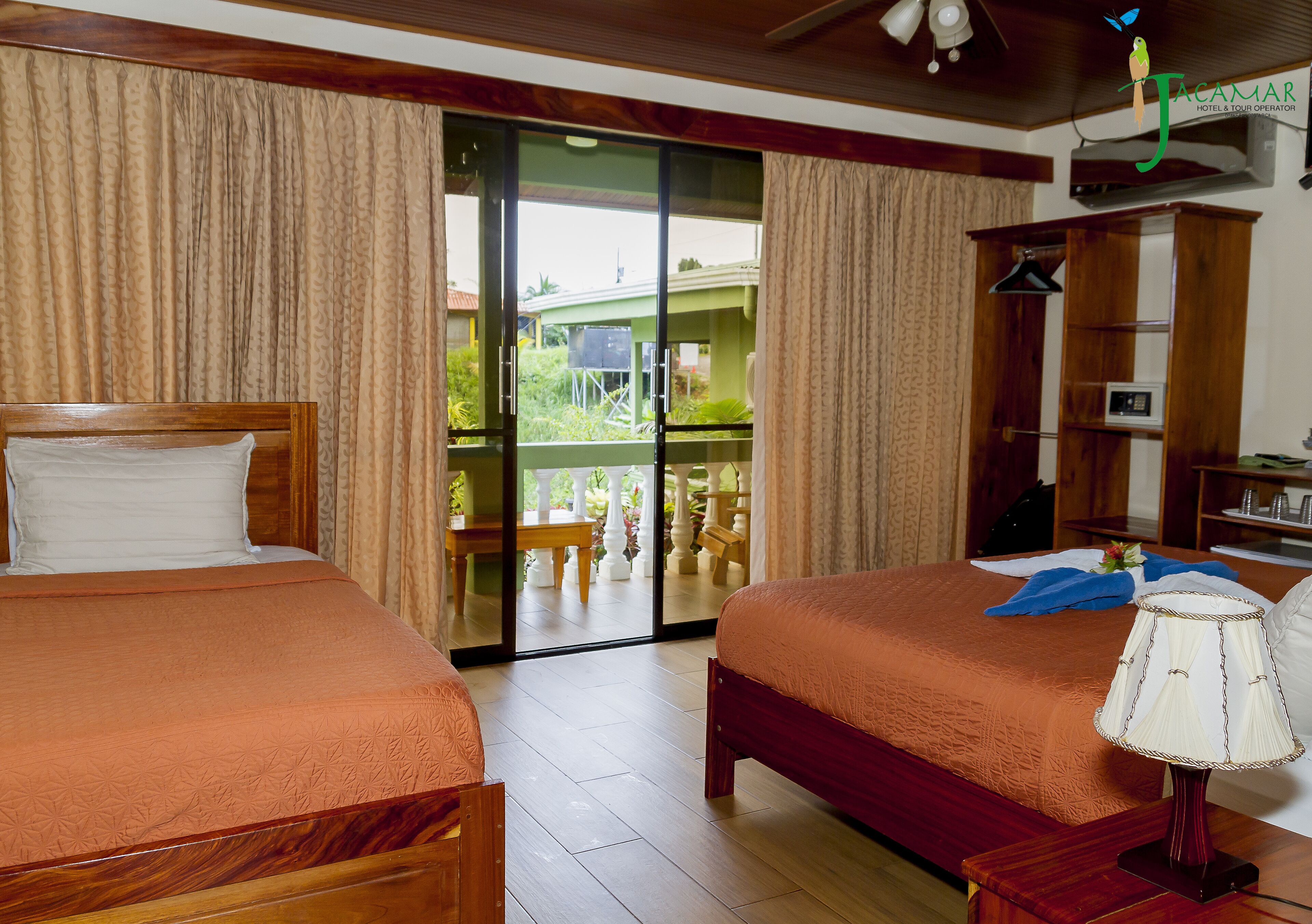 A hotel room with two beds, a balcony with a view, and a wooden ceiling.