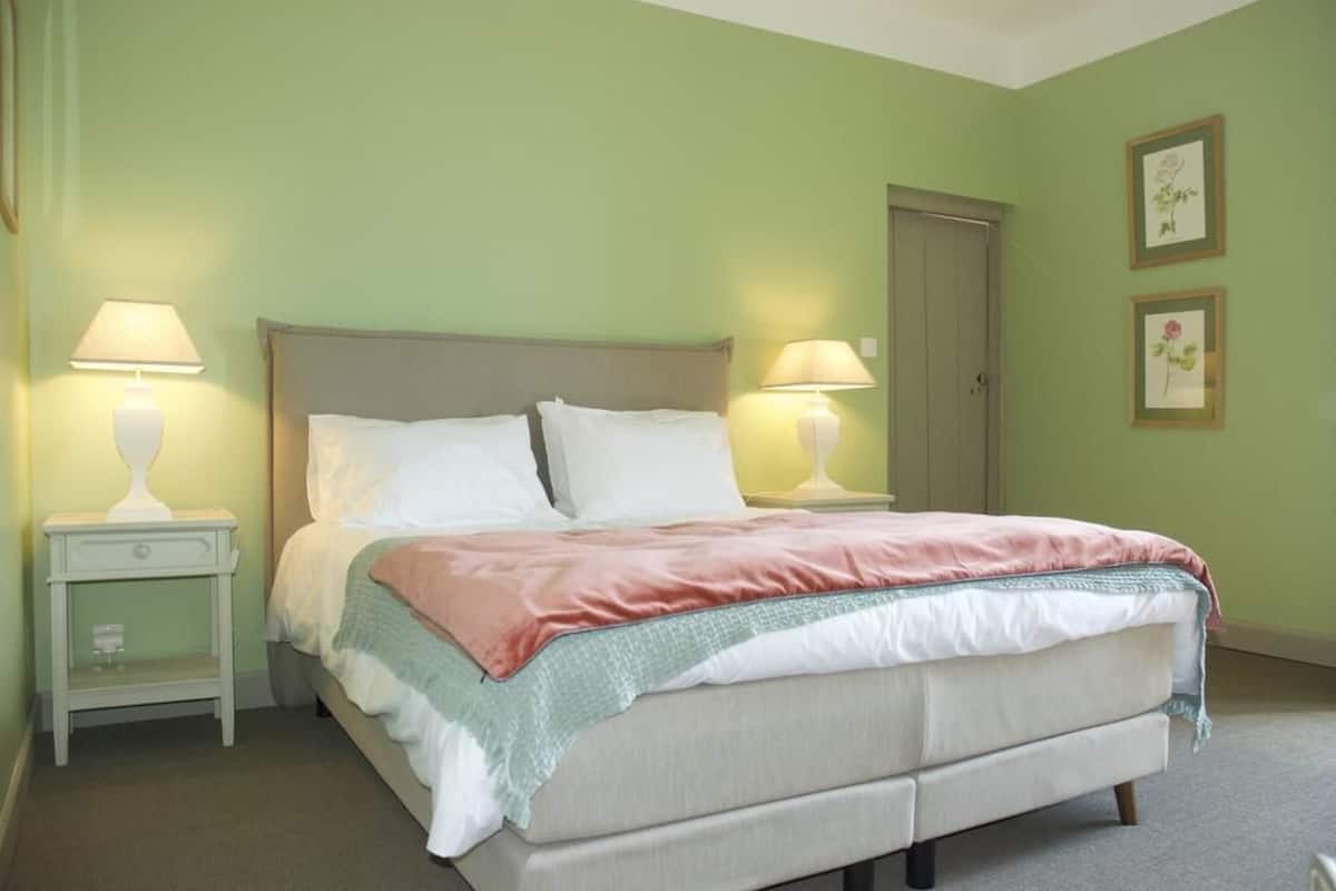 A neatly arranged bedroom with a bed, two bedside tables, and a door.