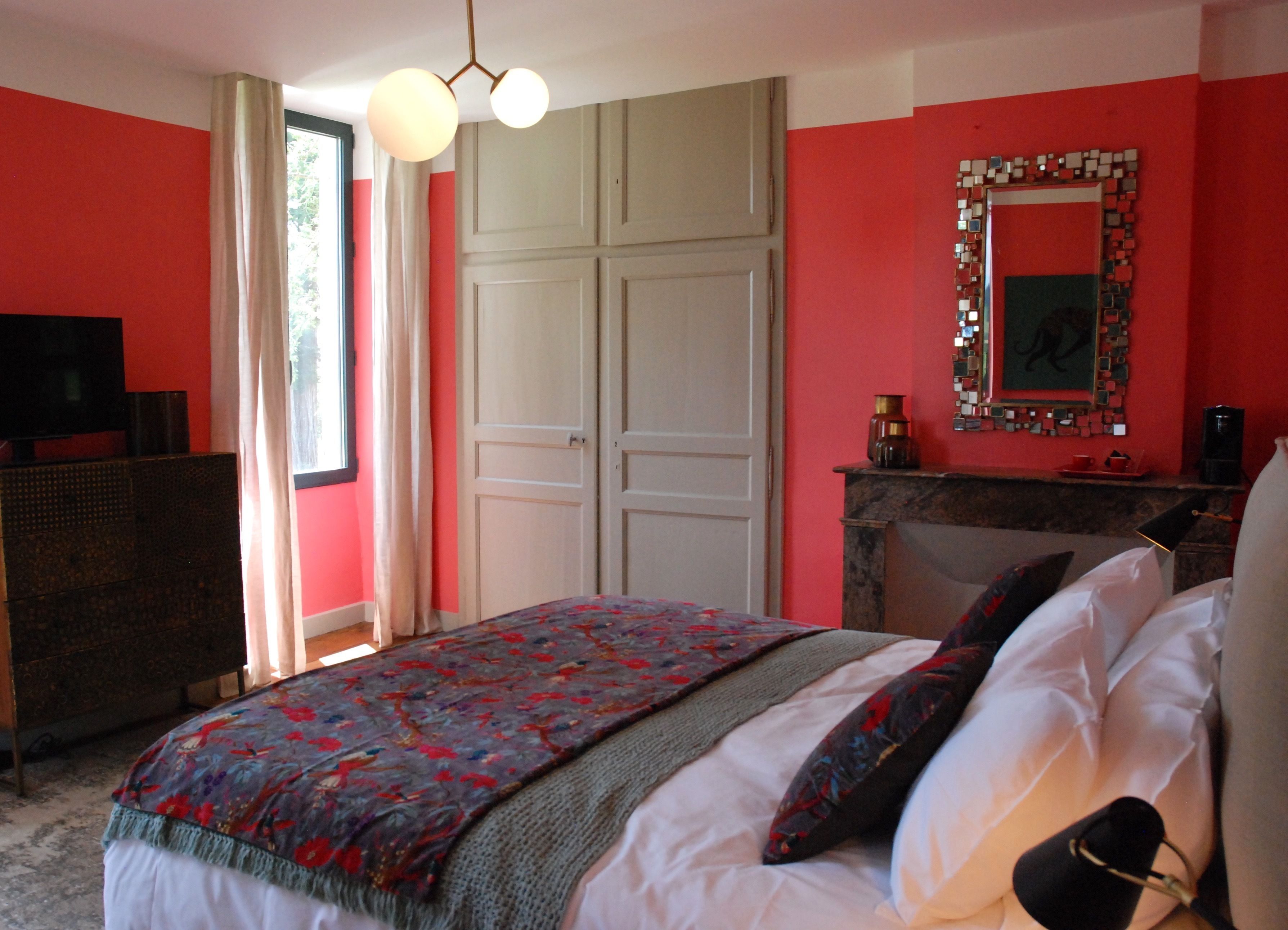 A bedroom with a bed, a dresser, a mirror, and a fireplace.