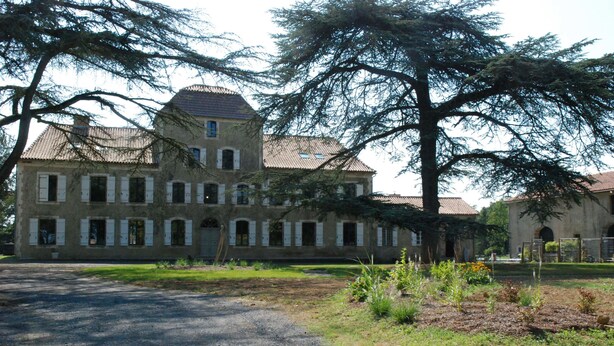A large, historic building with a symmetrical facade, multiple windows, and a central tower.