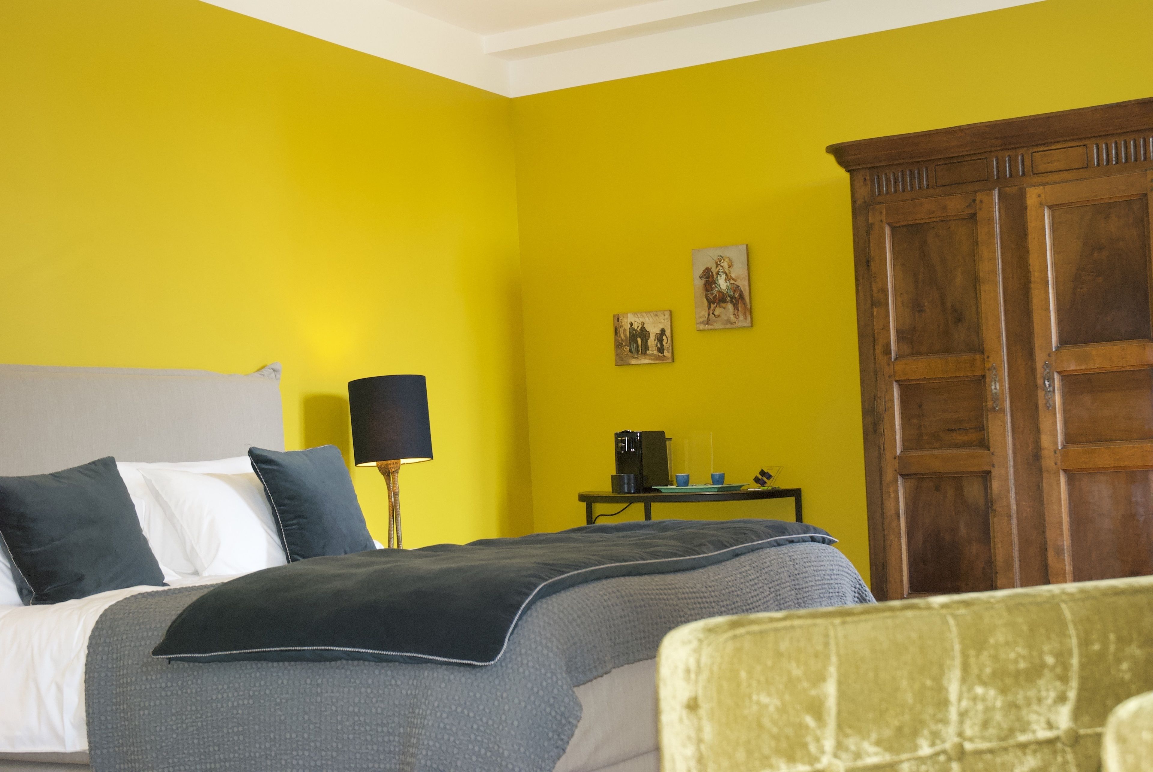 Ein Zimmer mit einem Bett, einem Nachttisch, einer Lampe, einem Holzschrank und zwei Bildern an der Wand.