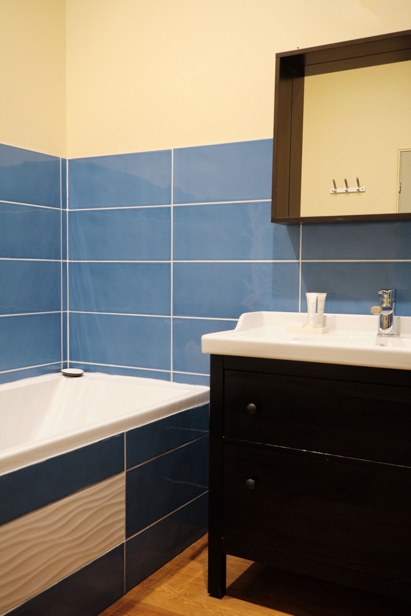 A bathroom with a bathtub, a sink, and a dark-colored vanity.