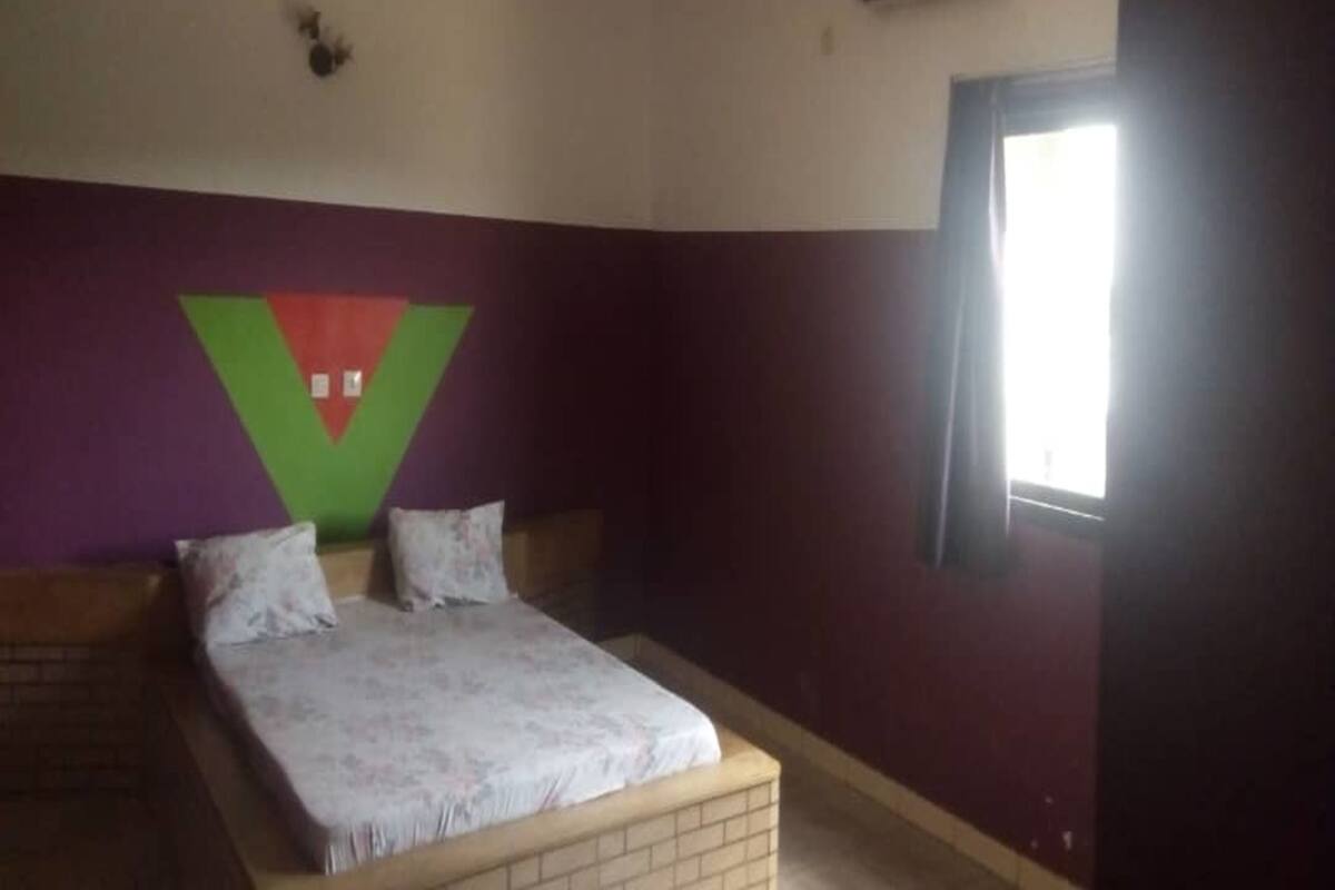 A bedroom with a bed, a window, and a wall with a large V-shaped decoration.