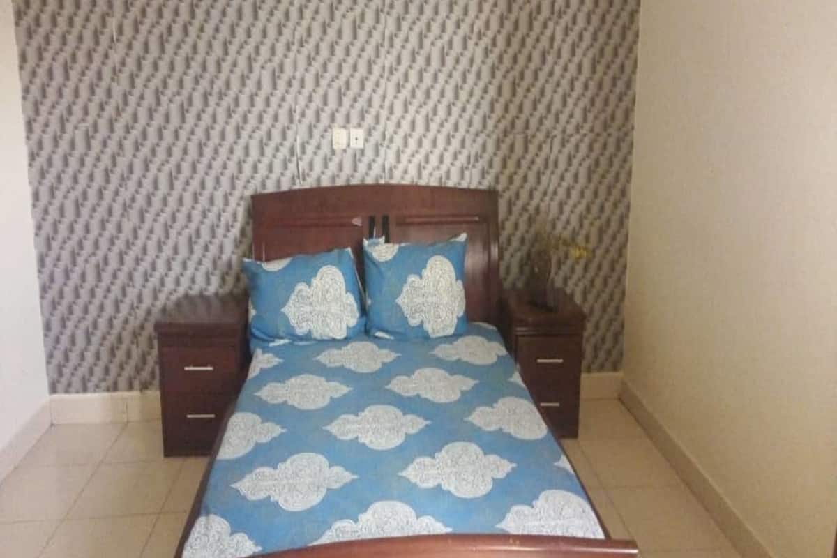 A bedroom with a bed, two nightstands, and a patterned wallpaper.
