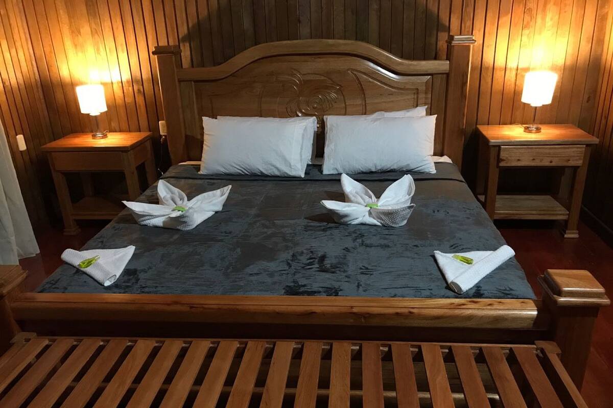 Una cama bien hecha con almohadas y toallas blancos dispuestos en un diseño decorativo.
