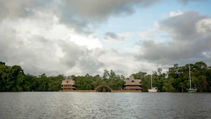 A large body of water with a bridge connecting two buildings, surrounded by dense greenery. - Tenamit Maya (Livingston)