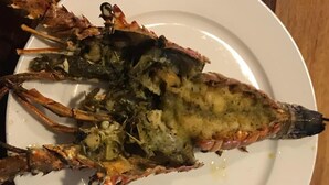 A plate with a cooked lobster on a white plate. - Tenamit Maya (Livingston)