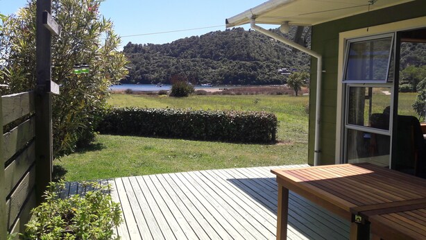 A wooden deck with a table and chairs, overlooking a lake and forested hills. - Ngakuta Bay, Marlborough Sounds. (Ngakuta Bay)