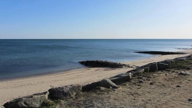 Una playa con costa rocosa y agua tranquila.