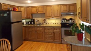 Una cocina con armarios de madera, un refrigerador, una estufa y un lavamanos.