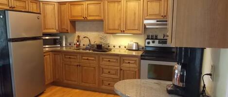 A kitchen with wooden cabinets, a stainless steel refrigerator, a stove, and a microwave.