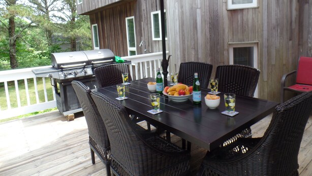 Un espacio para comer al aire libre con una mesa, sillas y una parrilla.