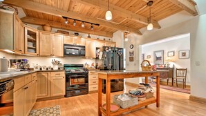 Una cocina con armarios de madera, una isla central y un comedor con una silla y una mesa.