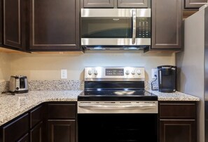 Fully equipped kitchen with a stove, microwave, and coffee maker.