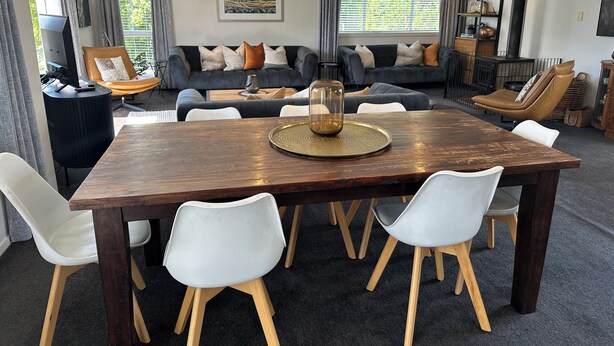 A modern living room with a wooden dining table, white chairs, a grey sofa, and a bookshelf. - Trout Retreat - Mountain, lake and river (Turangi)